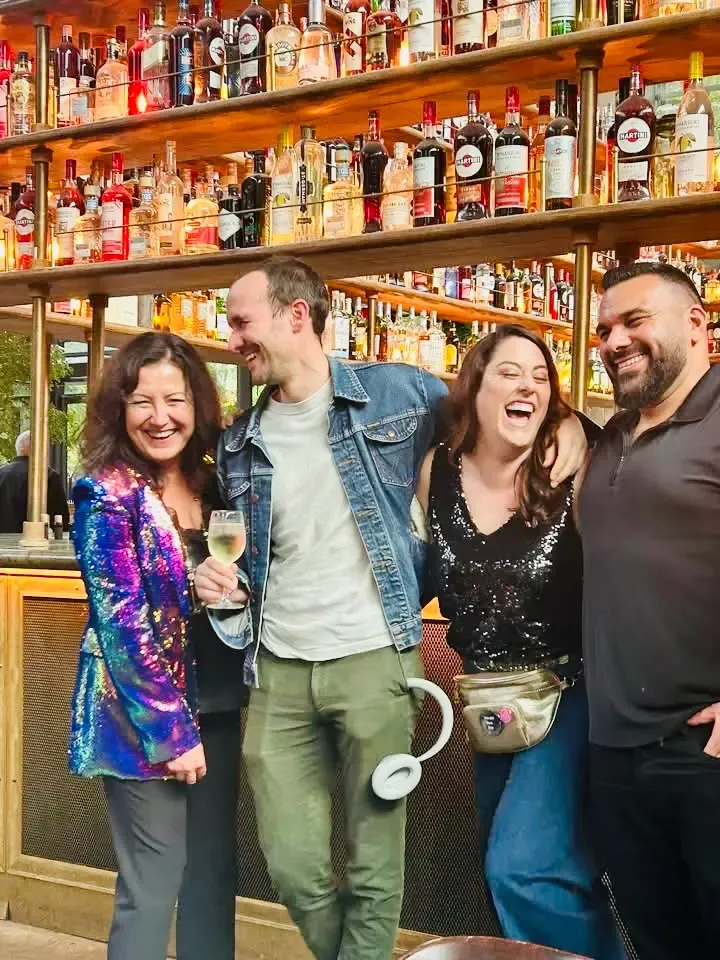 Estelle Hubert in a sequinned jacket with three VO Social Paris 2025 attendees in front of the bar at La Felicità