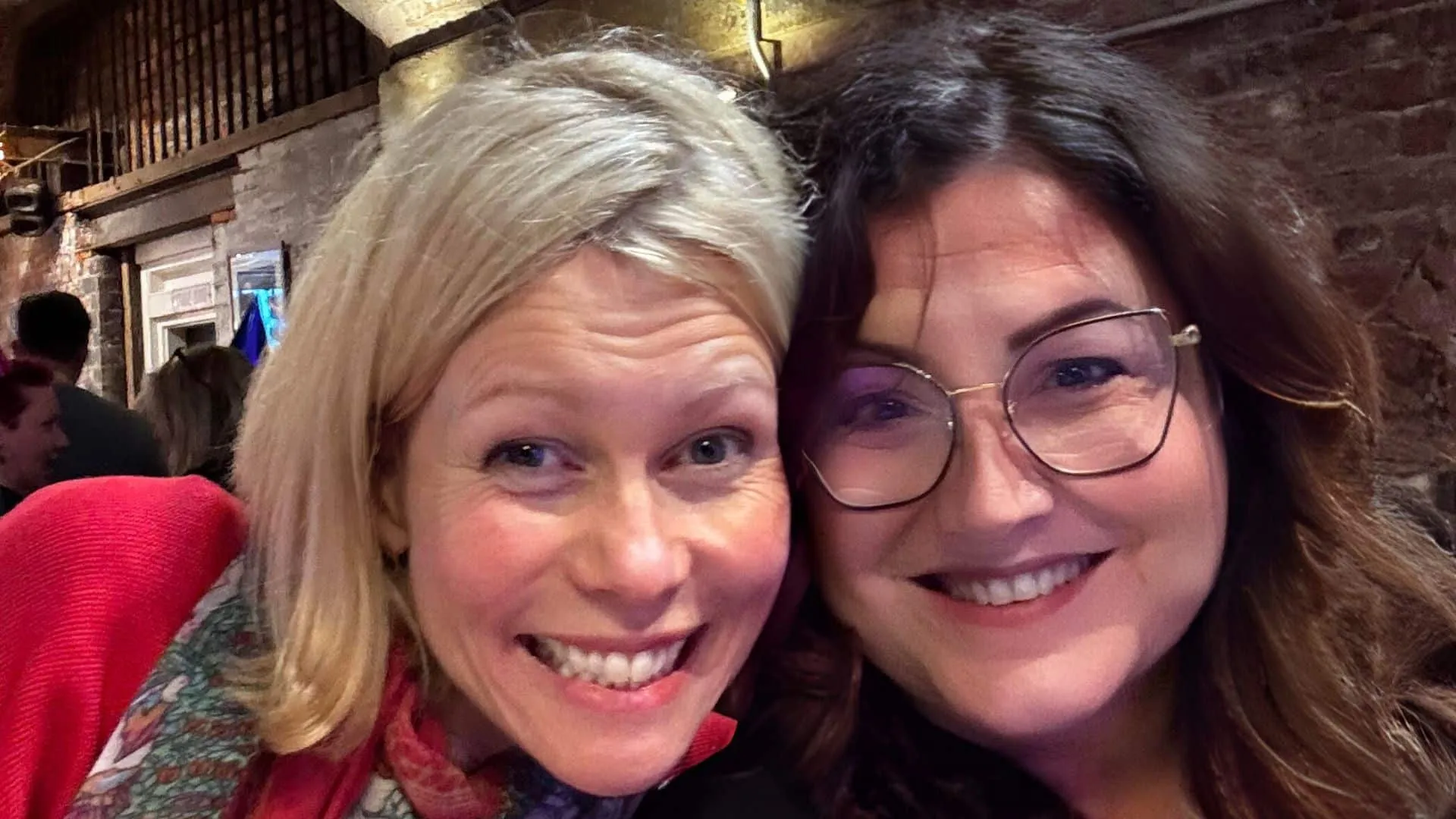 Katie Flamman et Estelle Hubert, comédiennes voix off, joue contre joue, souriantes, à Manchester