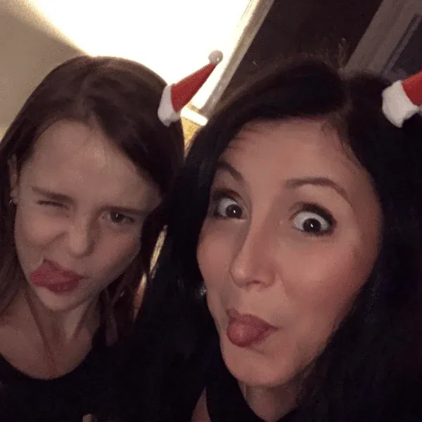 A younger Florine and Estelle Hubert pulling faces in a Christmas selfie, with little red hats on their heads