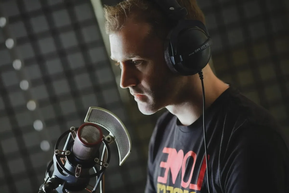 François Lidove au micro, casque sur les oreilles, concentré sur son texte, dans une cabine.