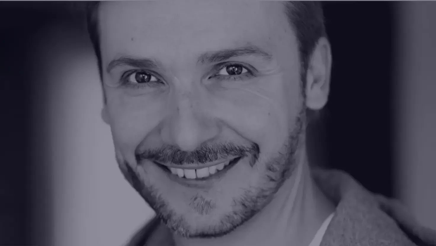 Portrait en noir et blanc d’Hervé Lacroix, comédien voix off, souriant, barbe courte