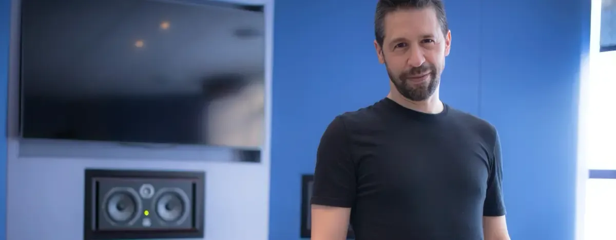 Sébastien Croteau, comédien voix off et coach, en t-shirt noir dans son studio d’enregistrement, devant une enceinte de monitoring