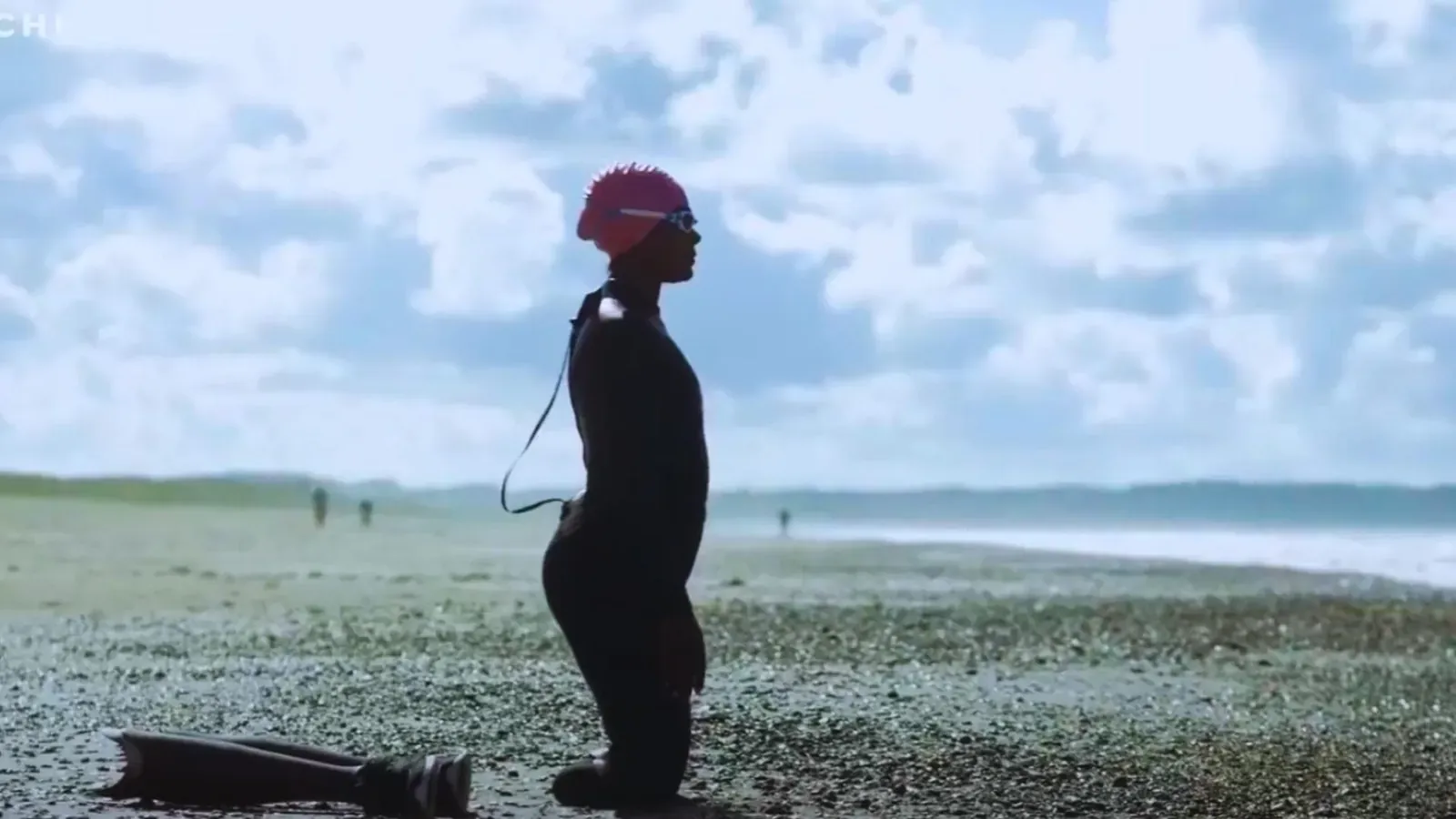 A woman’s silhouette on a pebble beach, facing the horizon