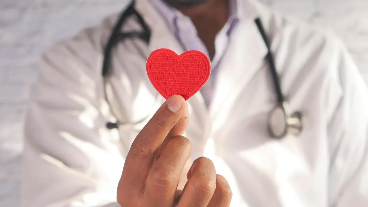 A doctor in a white coat holding out a red heart, from Siemens Healthineers medical e-learning