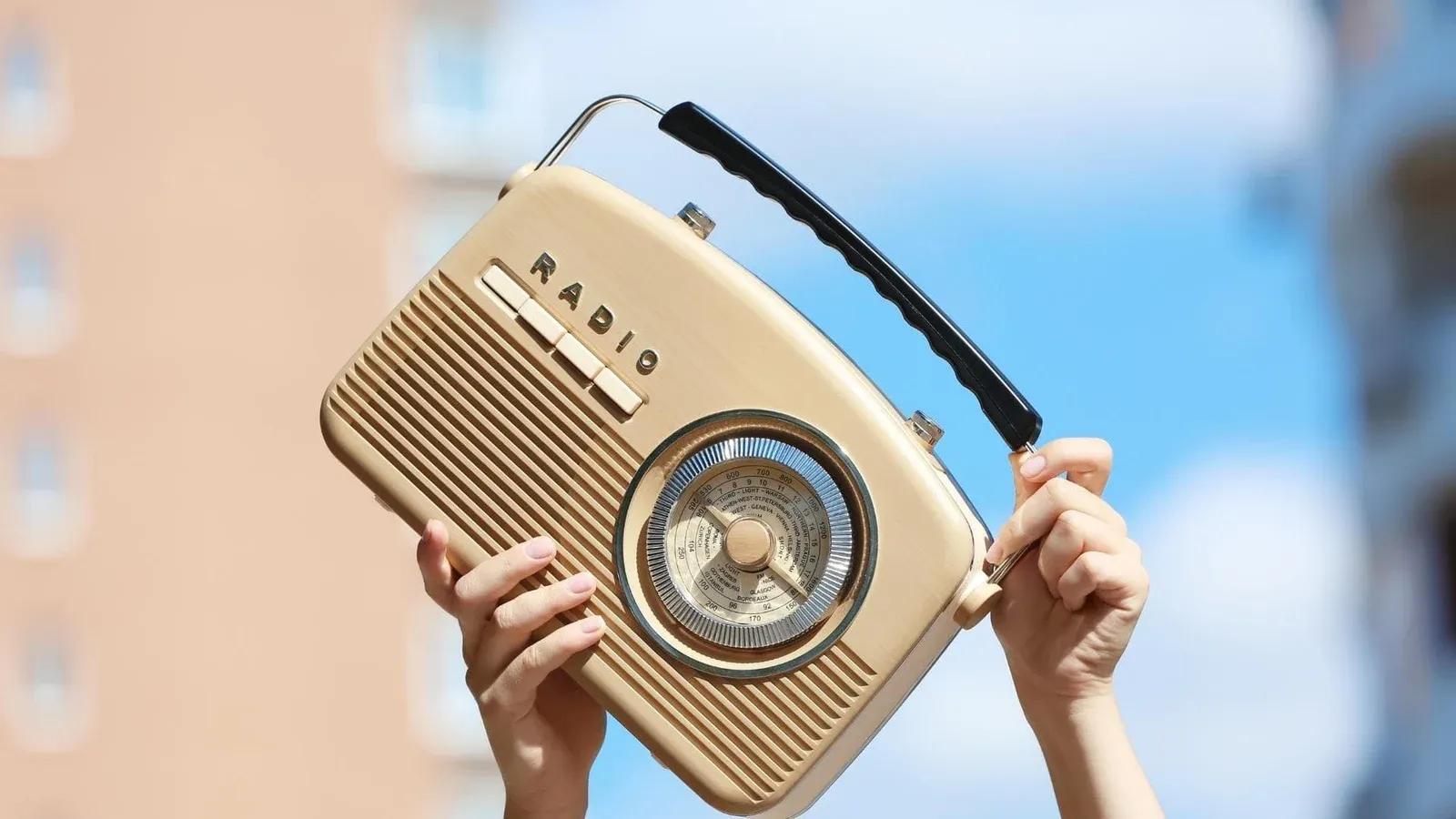 Poste de radio beige tenu entre deux mains, visuel de l’habillage de podcast