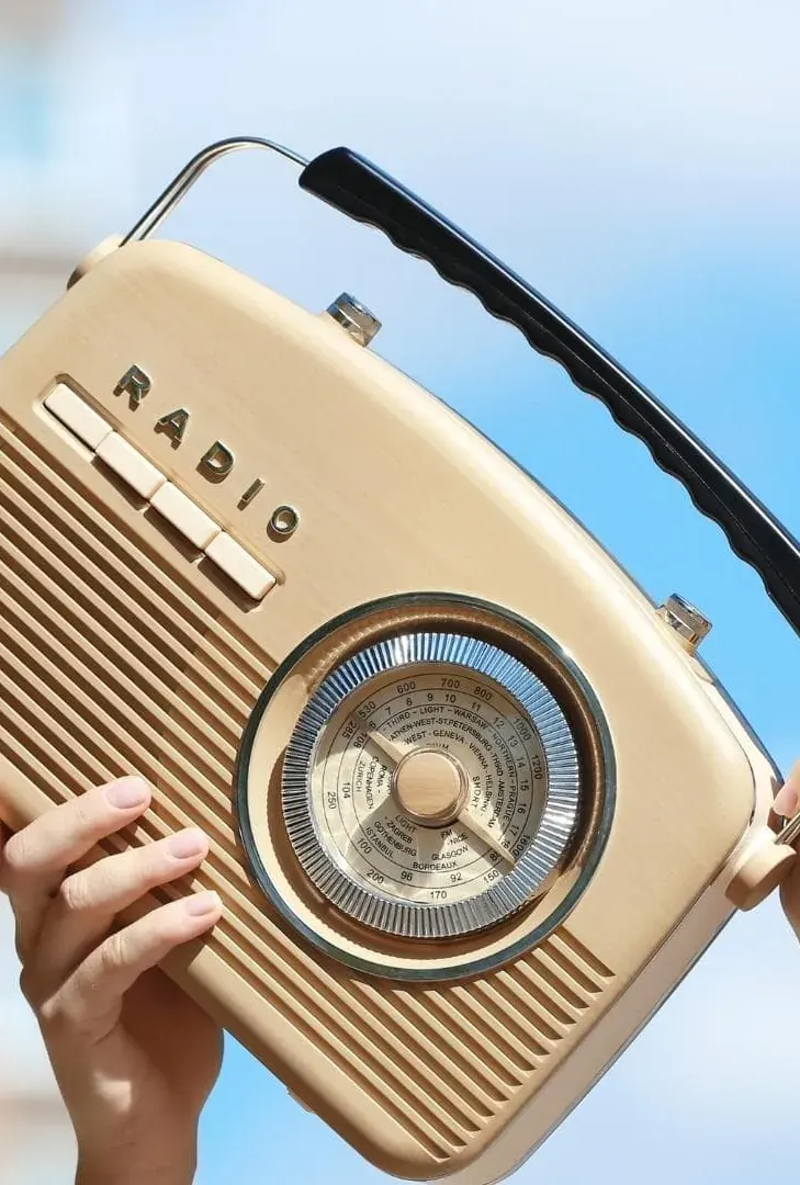 Mains tenant un poste de radio vintage devant le ciel, illustration de la spécialité radio et instore : Estelle Hubert, comédienne voix off