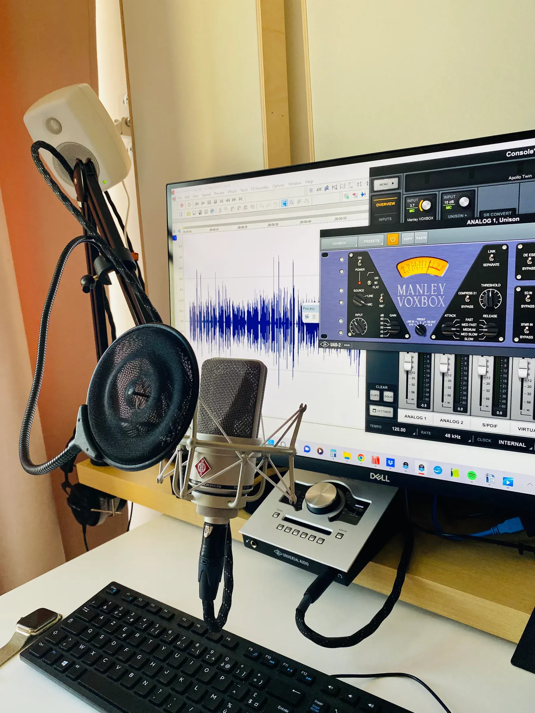 Studio Bis: Neumann microphone in a shock mount with a pop filter, an audio waveform on screen and an Apollo Twin interface on the desk