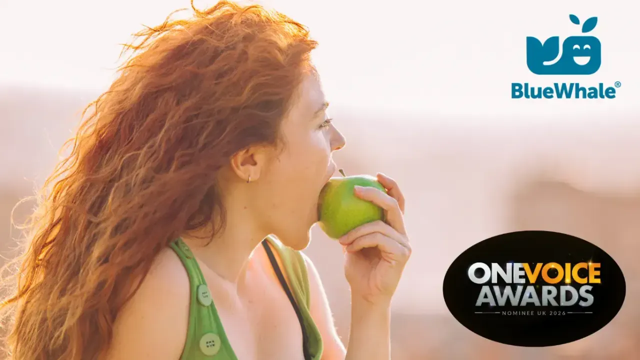 Femme aux cheveux roux croquant une pomme verte, logos Blue Whale et One Voice Awards