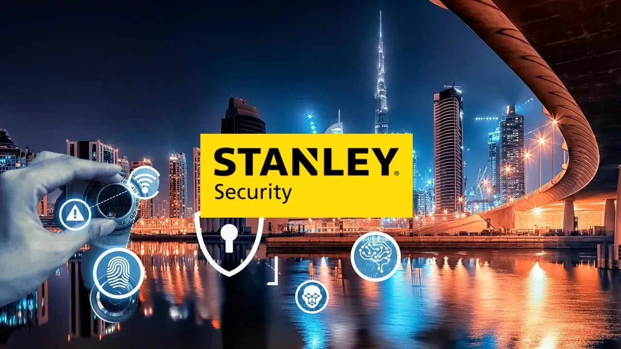 Main tenant un smartphone devant une ville illuminée, icônes de sécurité et logo Stanley Security