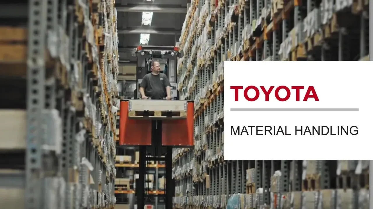 Cariste sur un chariot élévateur entre les rayonnages d’un entrepôt, logo Toyota Material Handling