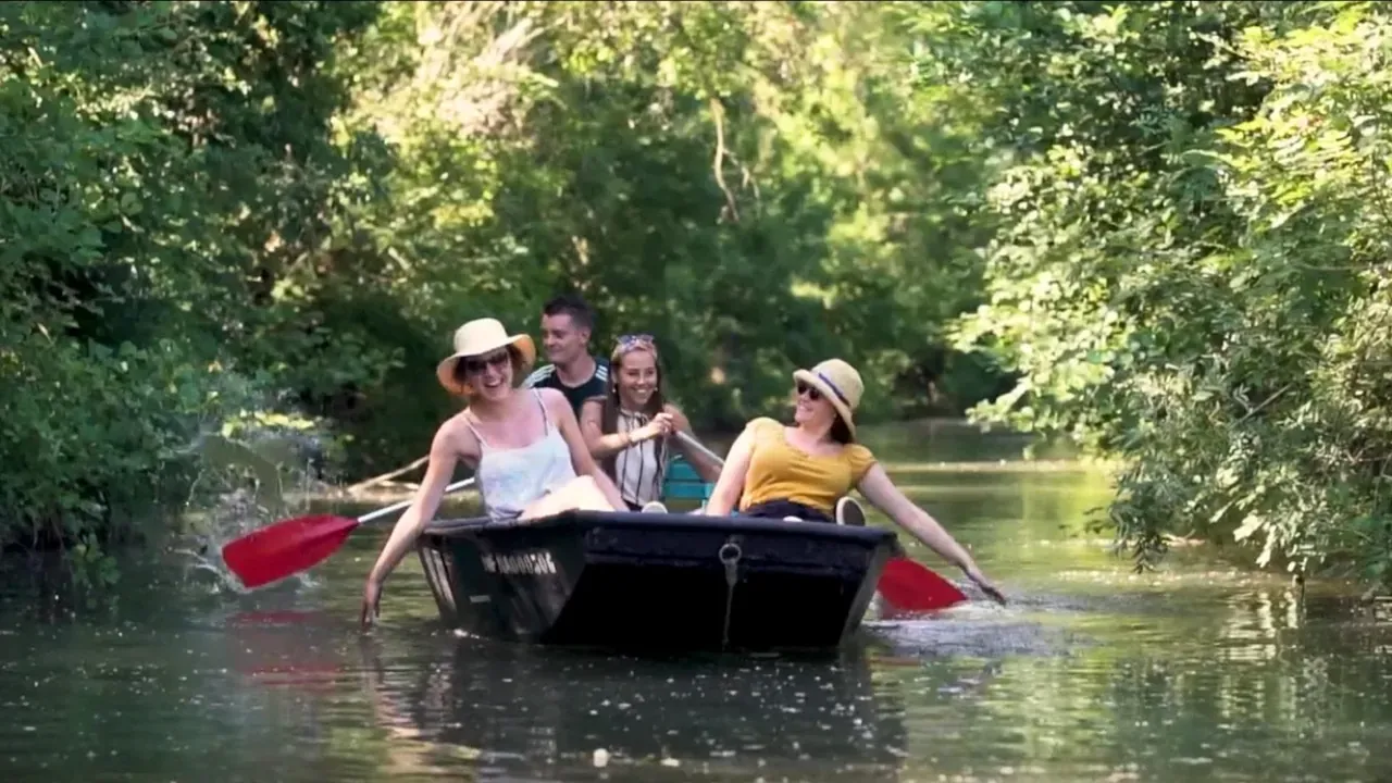 Famille en barque sur un canal bordé d’arbres, dans le marais
