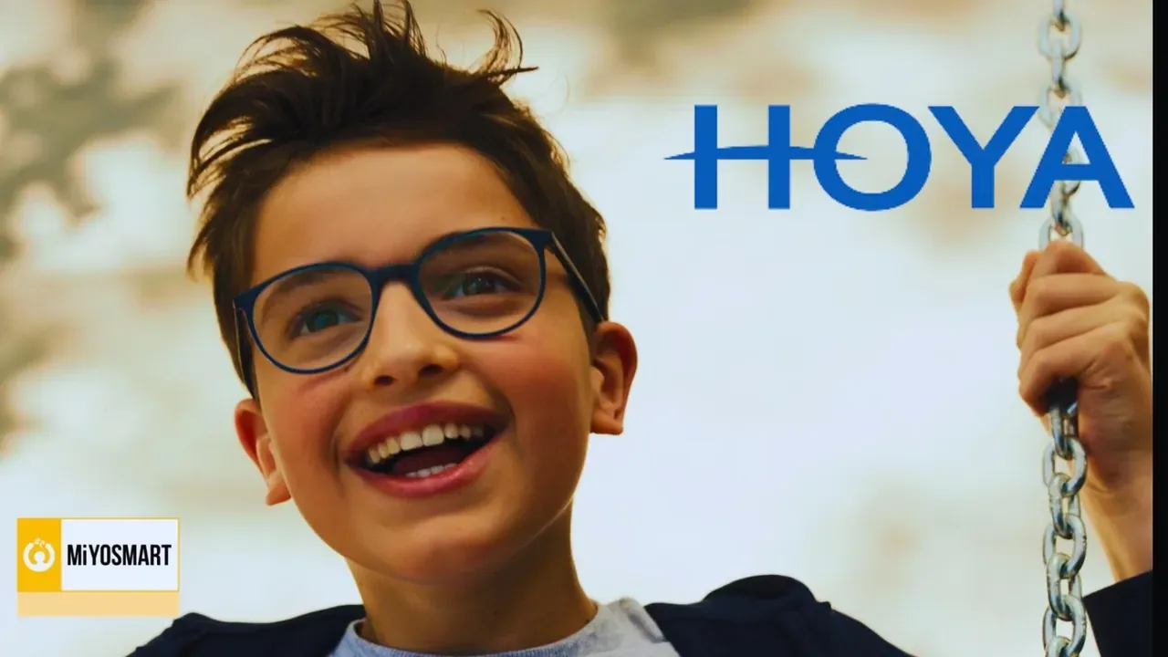 Garçon souriant à lunettes sur une balançoire, logos Hoya et MiYOSMART