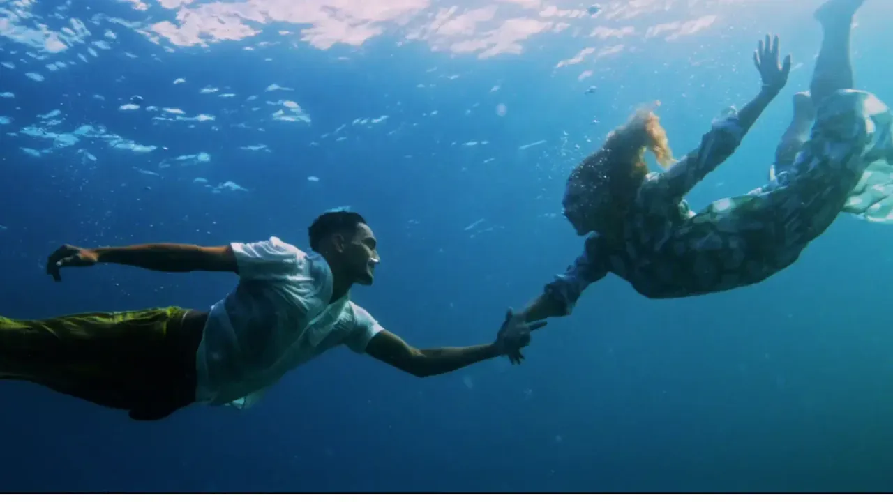 Deux nageurs se tenant la main sous une eau turquoise