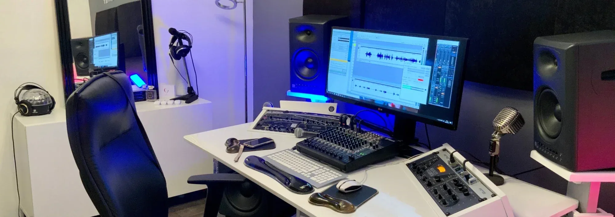 Control room du home studio d’Estelle Hubert, comédienne voix off, en lumière bleue : écran de montage avec l’onde du texte, console, channel strip Manley VoxBox, enceintes de monitoring et micro vintage