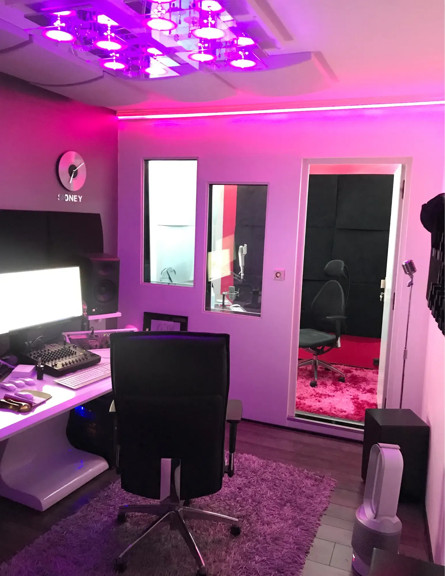 Estelle Hubert’s main studio: the control room in pink light, with the window and doorway looking into the recording booth and its microphone