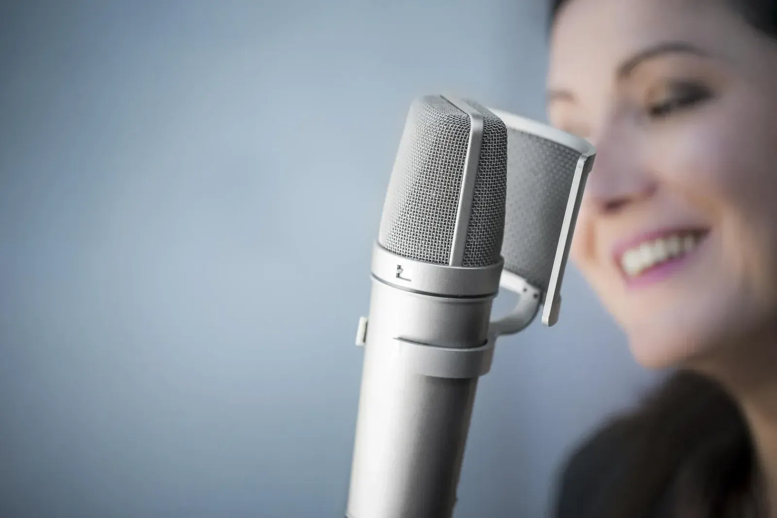 Microphone Neumann U87 devant Estelle Hubert, comédienne voix off, souriante dans la cabine de son home studio