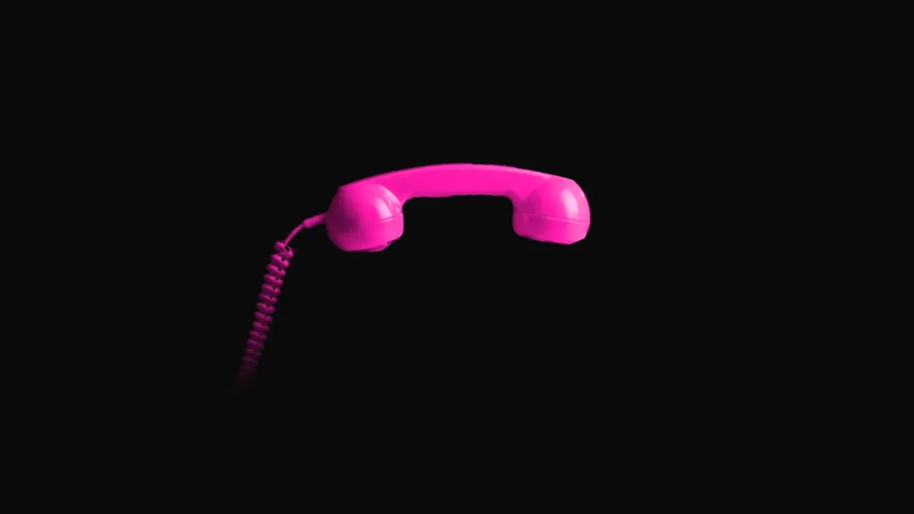 Combiné de téléphone rose fluo, seul, sur fond noir