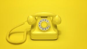 Téléphone vintage jaune illustrant l’attente téléphonique avec une voix off professionnelle par Estelle Hubert.